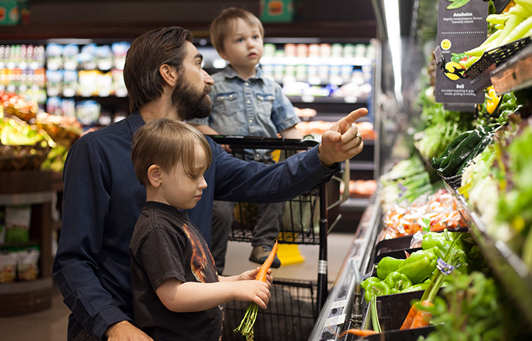 Father and son at the grocery store looking at the price of food.